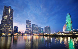 城市天際線，摩天輪在黃昏時分在水面上發光。 — 城市景觀 壁紙