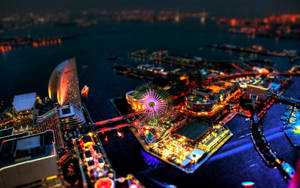 夜間海港，燈火通明的建築物和閃閃發光的摩天輪。 — 日落大道 壁紙