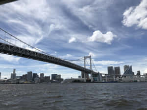 東京灣上的彩虹橋，城市天際線和漣漪水面。 — 4:3 壁紙