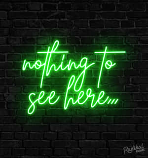 深色磚牆上一個寫著 nothing to see here 的綠色霓虹燈牌。