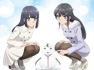兩個穿著冬季外套的女孩在雪景中與一個小雪人玩耍互動。