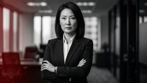 自信的商務女性身穿西裝，雙臂交叉站在辦公走廊。