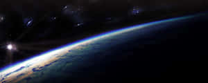 從太空觀看地球在日出時，背景有星星 — 寬螢幕 壁紙