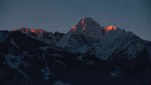 白雪皚皚的山脈在黃昏時分沐浴在金色的夕陽餘暉中。