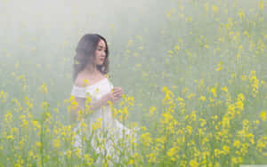 身穿白色連衣裙的女子坐在霧氣瀰漫的黃色花田中