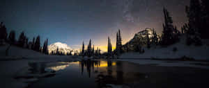 冰凍的湖面在黑暗的天空下反射出星星和雪山。