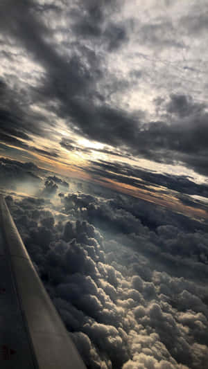 夕陽下飛機機翼在雲層之上，伴隨著戲劇性的暴風雲。