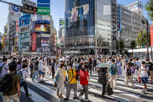 行人穿過東京一條繁忙的街道，有高樓大廈和明亮的招牌。