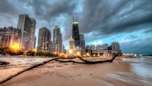 暴風雲下黃昏時分的芝加哥天際線，海灘和前景的倒下的圓木。