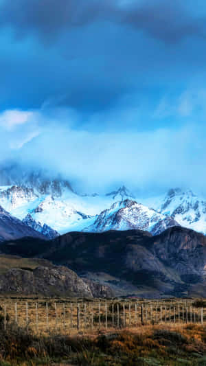 多雲天空下的雪山山脈，前景有木柵欄