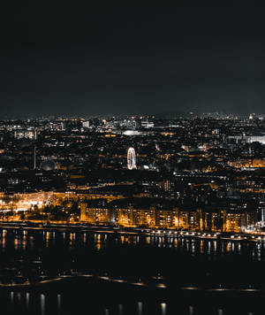 夜景城市景觀，燈光建築和摩天輪倒映在水中。