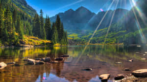 陽光穿過山峰，照耀在平靜的湖面上，周圍有森林和秋色。