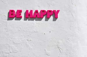 粉紅色3D字母寫著BE HAPPY，安裝在白色紋理牆上。
