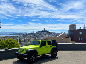 青檸綠色Jeep Wrangler在屋頂上，俯瞰三藩市日落時分的天際線。