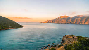 夕陽下的寧靜海灣，有山脈和綠色山丘 — 風景動圖 壁紙