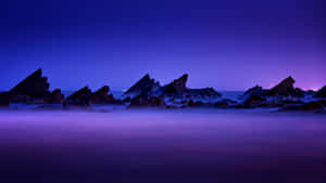 鋸齒岩石從霧氣瀰漫的水中浮現，背景是紫色暮色天空。