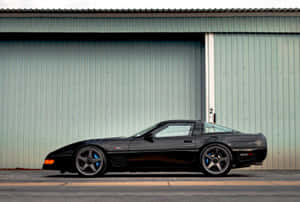 黑色Corvette Z06停泊在綠色金屬車庫門前。