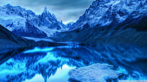 白雪覆蓋的山脈倒映在藍色湖泊中，有一塊漂浮的冰塊。