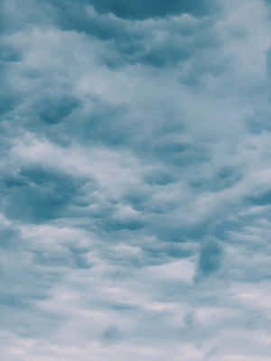 戲劇性的青綠色和灰色雲朵佈滿陰沉的天空，呈現出陰鬱的自然景象。 — 天氣 壁紙