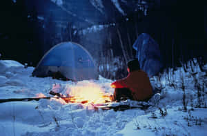 人在雪地森林夜晚中於營火旁取暖，有帳篷