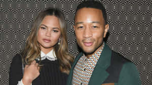 Chrissy Teigen 和 John Legend 在幾何圖案牆前擺姿勢。 — Beyoncé 壁紙