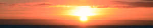 夕陽映照海洋，天空呈現鮮豔的橙色和金色