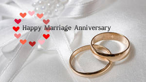 兩枚金色結婚戒指放在白色緞帶上，帶有心形和週年紀念文字。