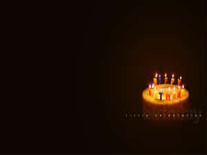 一個生日蛋糕上點燃的蠟燭在黑暗中拼出 happy birthday。