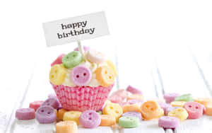 裝飾著彩色鈕扣糖果和happy birthday牌子的生日杯子蛋糕。
