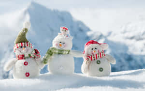 三個戴著帽子和圍巾的雪人公仔在雪山上。
