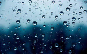 玻璃上的雨滴與模糊的藍灰色背景