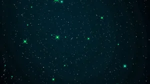 一個繁星點點的夜空,帶有發光的綠色星星和藍綠色漸變。