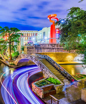 夜間運河上的石橋，帶有藍色和紫色的光軌條紋。