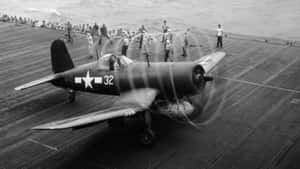 復古軍用飛機在航空母艦甲板上，船員在周圍