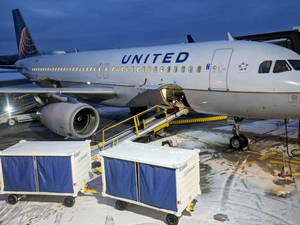 聯合航空飛機停在積雪的停機坪上，有登機梯和行李車。