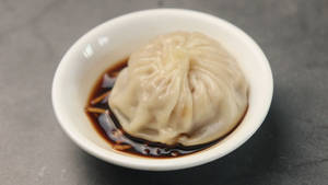 灰色石上白色碗中的醬油蒸餃。