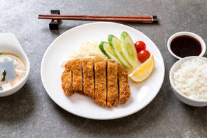 切片炸豬排配米飯、青瓜、番茄和醬汁，置於灰色石面上。 — 美食 壁紙