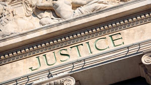 法院大樓特寫，刻有 'justice' 同上面嘅石雕。