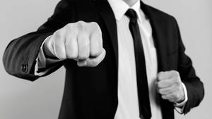 穿西裝的男子在黑白中向前揮拳。