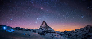 在紫色和橙色色調的星空暮色天空下的白雪覆蓋的山峰。 — 月色夜空 壁紙