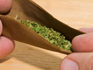 雙手在木桌上捲大麻煙。
