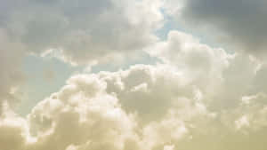在淡藍色天空的映襯下，密集的白雲被金色的陽光照射。