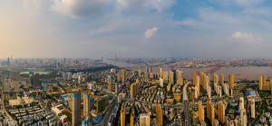 密集現代城市的全景高空景觀，有河流和橋樑。 — 日落大道 壁紙