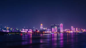 夜晚的城市景觀，建築物發光，水面有色彩繽紛的倒影。 — 紐約市夜晚 壁紙