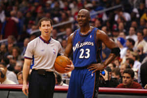 身穿巫師隊球衣的米高佐敦在NBA比賽中，拿著籃球站在裁判旁邊。 — 邁克爾·喬丹 壁紙