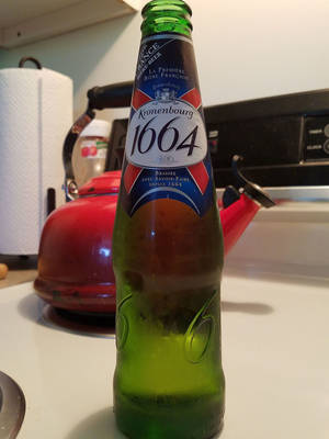 廚房枱上紅色水煲旁邊嘅綠色Kronenbourg 1664啤酒樽。