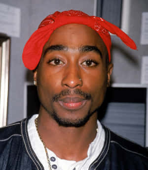 Tupac Shakur 戴住紅色頭巾同牛仔褸，望住鏡頭。