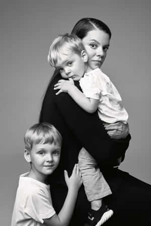 一位母親抱著幼兒，旁邊站著一個小男孩的攝影室肖像。