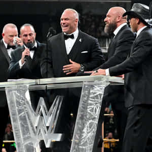 WWE摔角手穿著禮服在正式活動中在講台上笑。 — 摔角 GIF 壁紙