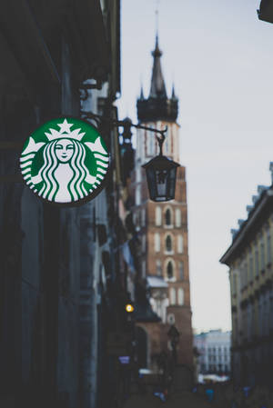 Starbucks標誌在街上，背景有一座歷史塔樓。